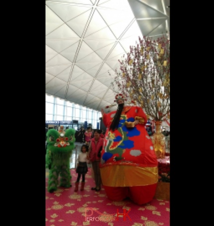 HK stilt-walker in giant inflatable Choi Sun costume at airport Chinese New Year event