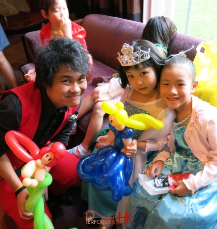 Roving Balloon artist in HK twisted two princess balloons for two children dressed in a Elsa costume at a kids birthday party
