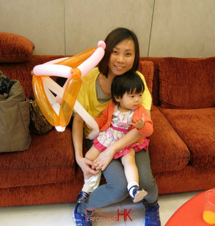A lady in Hong Kong taking photo with her little girl who holding a umbrella balloon gift form a balloonist in Hong Kong