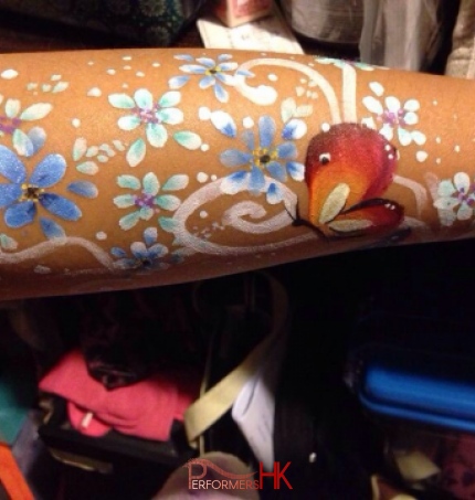 A face painter finished a beautiful flower and butterfly paint on arm at a Hong Kong family fun day event