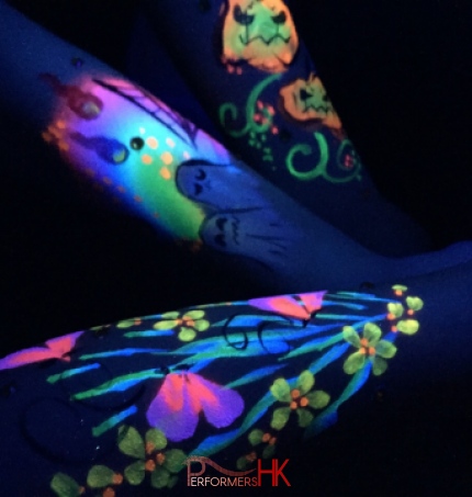 HK face painter draw a painting on hands with UV paint , the paintings are glowing under UV light at a corporate Halloween event
