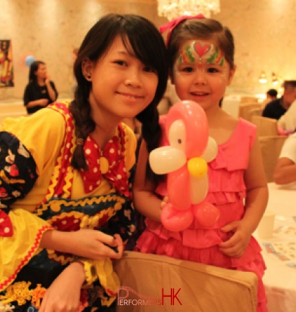 Hong Kong walk around balloon twister dress as a clown with a Mickey Mouse clown costume taking picture with a little girl wearing pink ,holding a pink Pingu at a Children birthday party