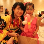 Hong Kong walk around balloon twister dress as a clown with a Mickey Mouse clown costume taking picture with a little girl wearing pink ,holding a pink Pingu at a Children birthday party