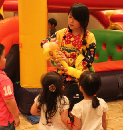 Balloons artist in Hong Kong twisting a flower for three children