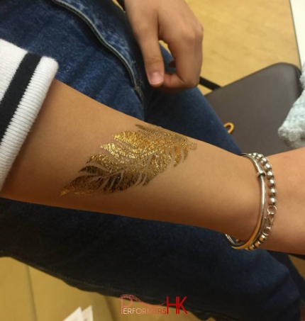 A guest choose a leaf shape gold tattoo on her hand at a school fun day event