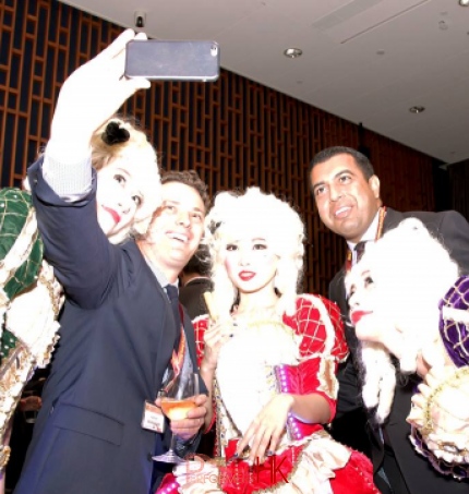 Three performers wearing victorian costume taking picture with guest in a corporate cocktail setting