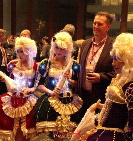 Three  model dancers in period attire taking picture with business men