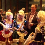 Three  model dancers in period attire taking picture with business men