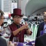 Magician in purple suit with a purple top hat performing table magic to four gentlemen at Hong Kong Happy Valley Races 