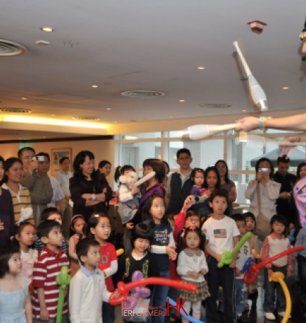Juggler in HK performing unicycle with 3 cups at a Children event