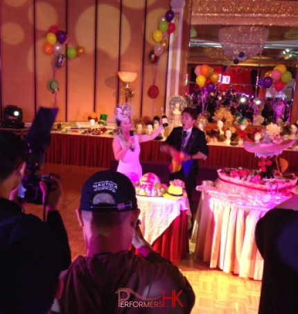 Hong Kong Magician performing roving magic with the birthday lady who holding a bottle of wine at a hat theme adult birthday party