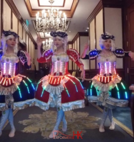 Three dancers wearing victorian era dresses with LED lights