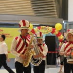 Three strolling musicians wearing colorful candy cane vests in a mall