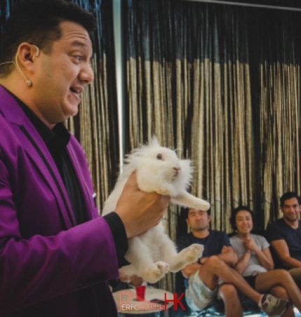 Hong Kong Magician in purple suit performing magic with a live bunny at a corporate event