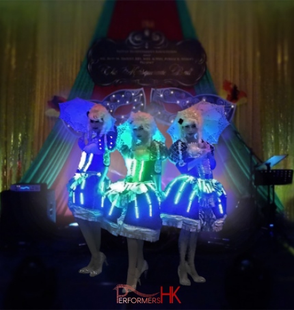 Three dancers in period costume with LED lights and umbrellas