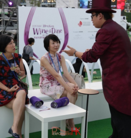 Roving magician at an exhibition in Hong Kong preforming a card trick to two girls