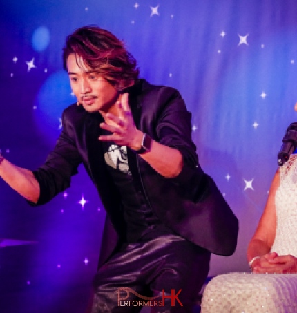 Magician standing next to the table with a lighted candle on it , performing stage magic to the chairwoman at Hong Kong Dog Rescue annual dinner in Aberdeen Marina Club 