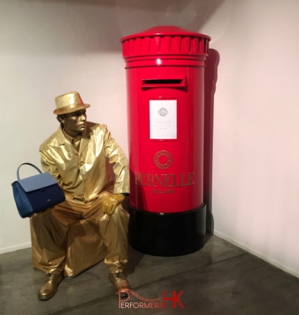 Living Statue holding handbag sitting next to red post box in hong kong 