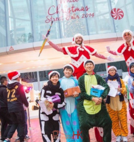 Two Xmas red and white stilt walkers standing behind a group of animal costume models