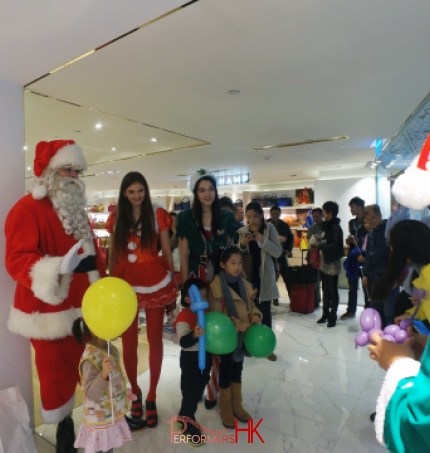 Santa performer with Santa girl and Elf models having a picture with three little kids who holding balloons at a Xmas event in Hong Kong 