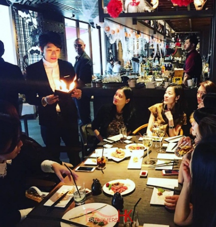 Magician performing roving fire magic to ladies at a Hong Kong restaurant