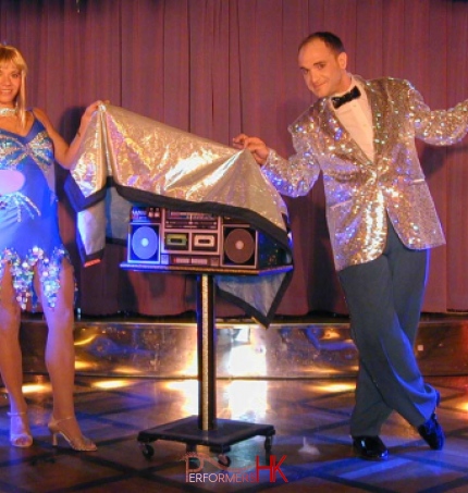 Talented stage magician in Hong Kong and his assistant performing a great show ,they are covering the radio between them with a sliver cloth at a festival function