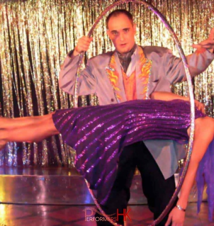 The beautiful lady is levitating and the magician in HK is holding a huge ring to show the audience there is no wires to keep the lady in the middle of the sir at a company function