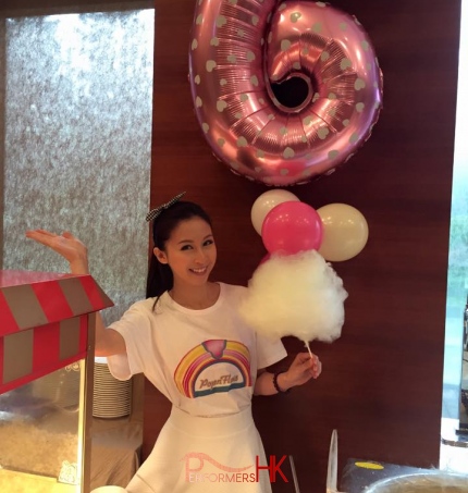 Model serving candy floss with popcorn machine in foreground
