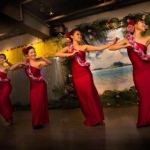 Four female dancers dressed in red performing hula and Tahitian dance. 