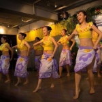 Seven female hula dancers doing hula chants and dancing for the audience. 