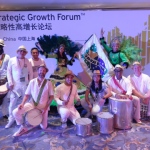 Percussion performers in white and dancers in green posing for photo