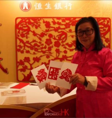 chinese artist cutting zodiac handicraft wearing red at Hang Seng bank in Hong Kong
