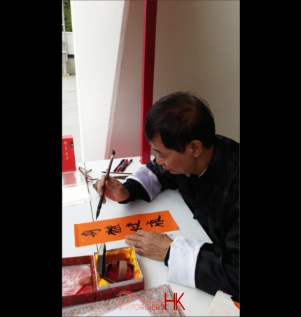 hong kong artist in traditional costume working on auspicious writings
