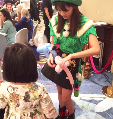 balloon twister genie in green elf costume twisting balloon for child at shangri la hong kong central