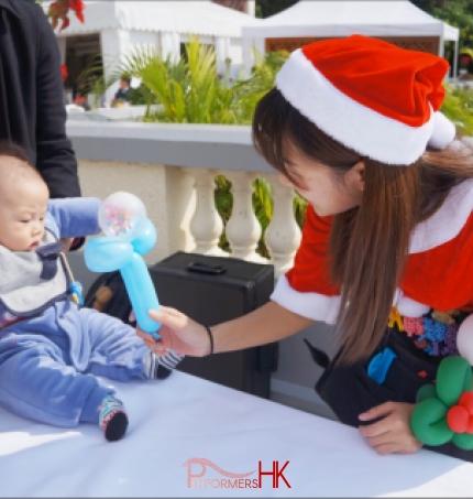 child being passed a balloon by balloon twister genie in red costume at 109 repulse bay hong kong christmas time 