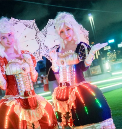two led costume character at hong kong harbour front in july for the hktb festival with parasols and in led costume one in red and another in purple