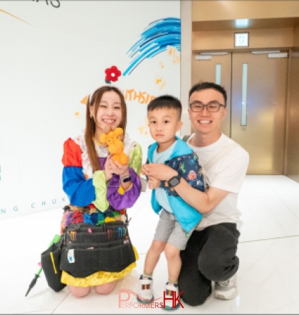 Cory balloon twister in colorful costume, holding a balloon sclupt of a dog