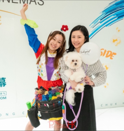 Cory with a shopper holding a dog taking a picture holding her hand in the air