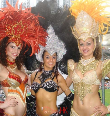 three Samba dancers in red, black and gold at Hong Kong Rugby Sevens